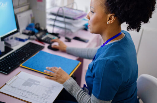 Black woman using computer to work as nurse in the private clinic.